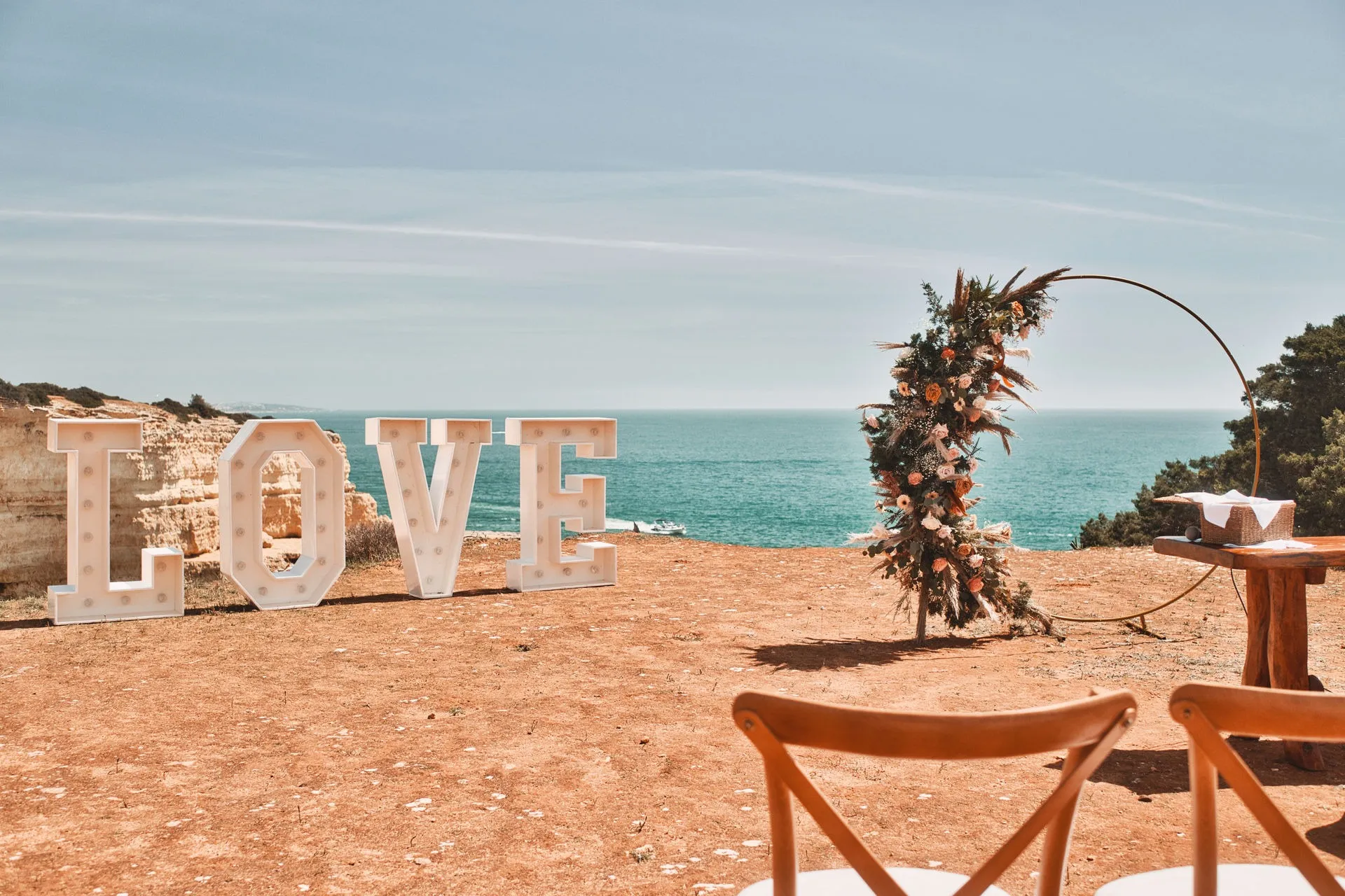 Letras LOVE e arco floral redondo em frente ao mar