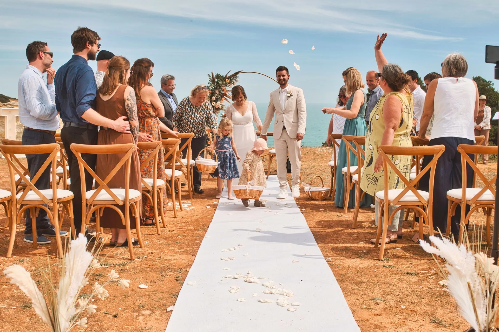 Recém-casados a sair enquanto os convidados lançam pétalas